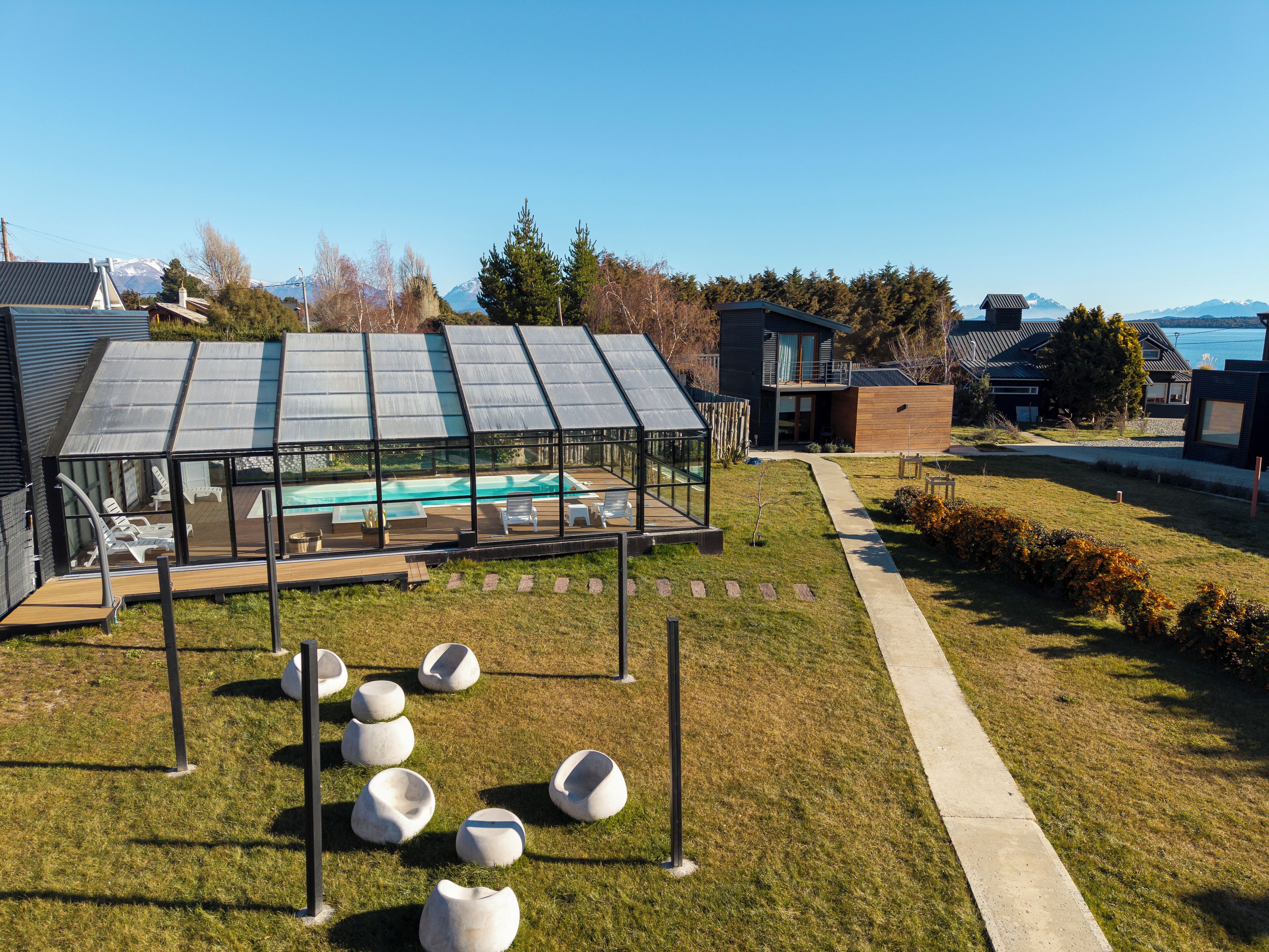 Een modern buitenzwembadgedeelte met een glazen omheining, ligstoelen en unieke zitzakken.