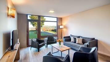 A modern living room with a sofa, two armchairs, a coffee table, and a television.