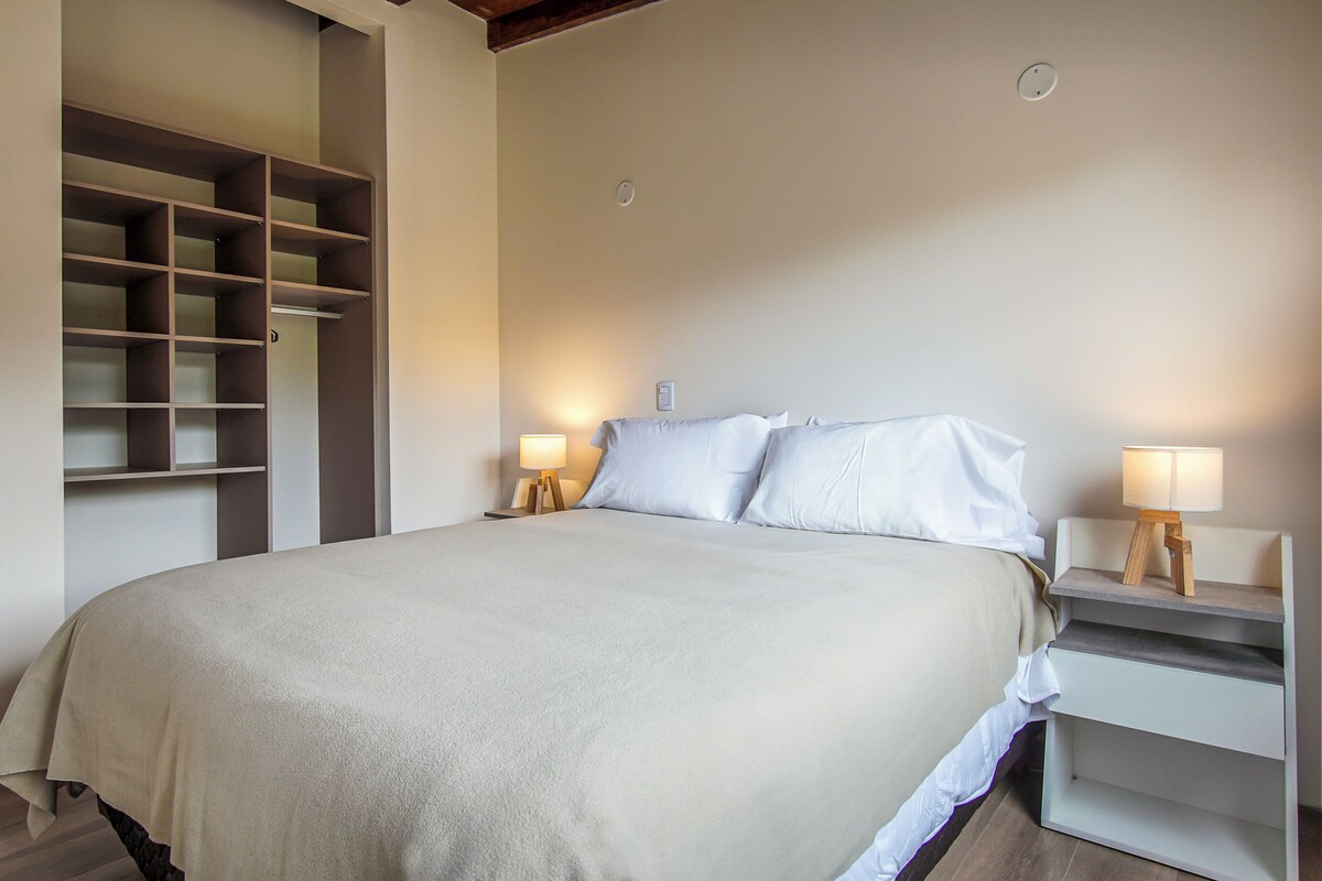 Une chambre à coucher comprenant un lit, des tables de chevet, une armoire et une petite table de nuit avec une lampe.