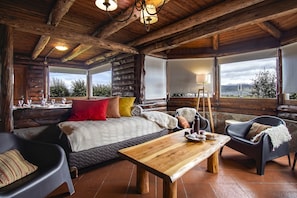 Une chambre rustique aménagée dans un chalet en rondins, avec un lit, une table en bois, un canapé et une chaise.