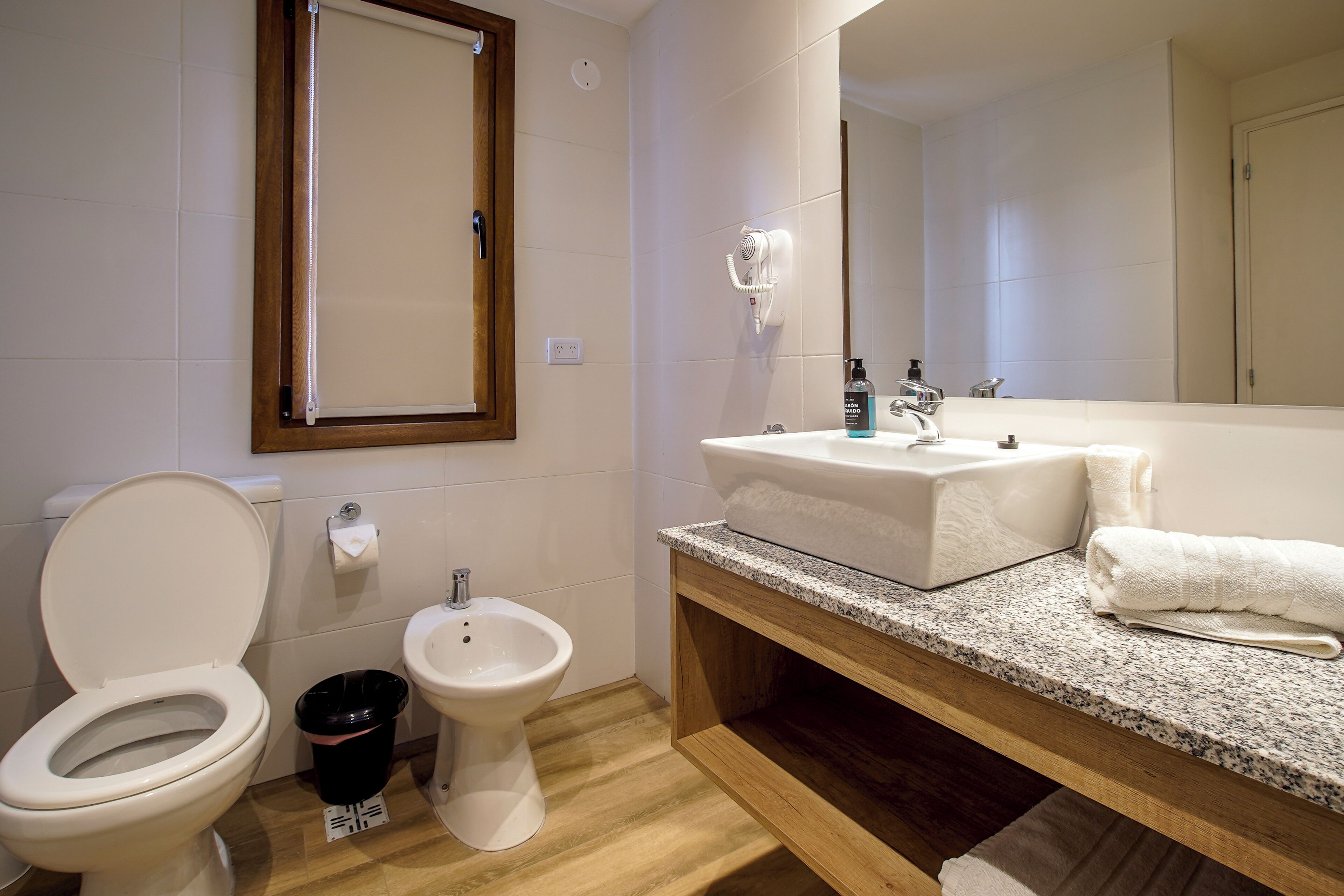 A bathroom with a toilet, bidet, sink, and mirror.