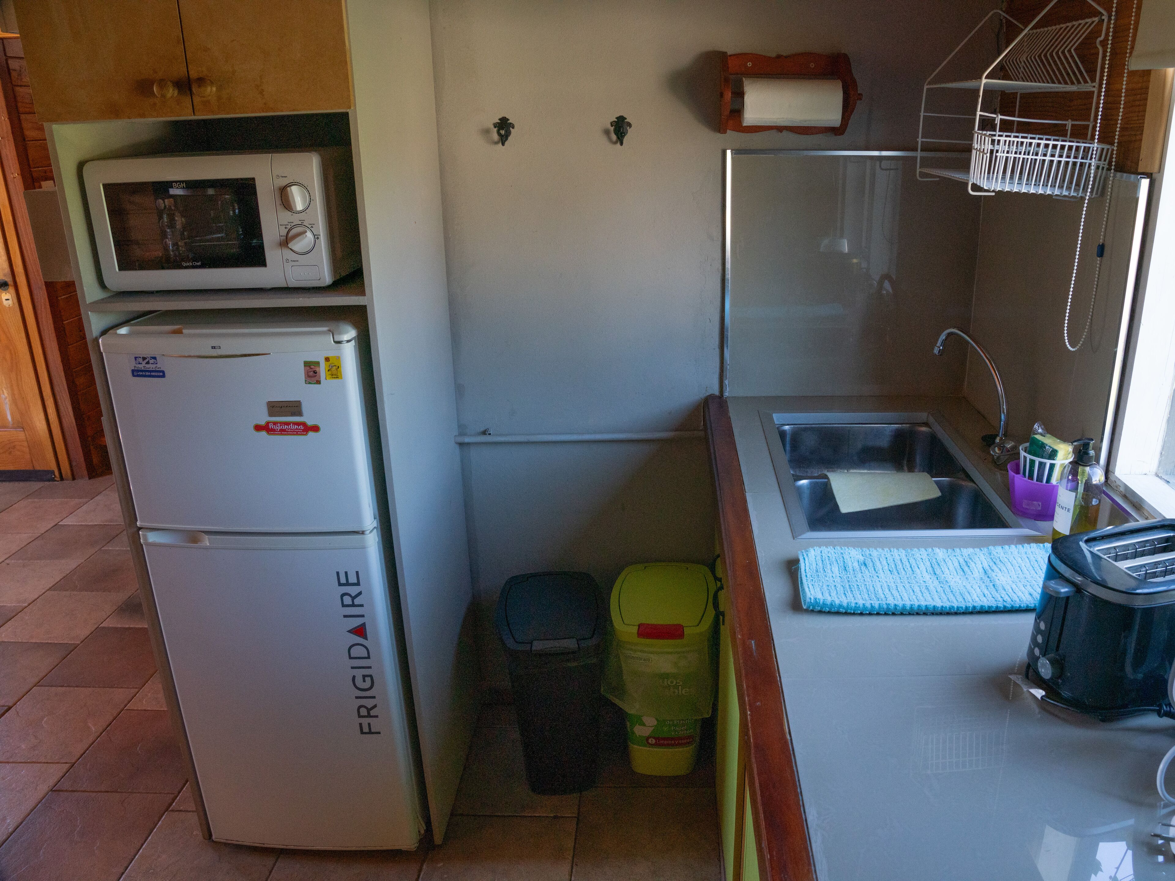 Una cocina compacta con un refrigerador blanco, un microondas, un lavamanos y un ventanal pequeño.