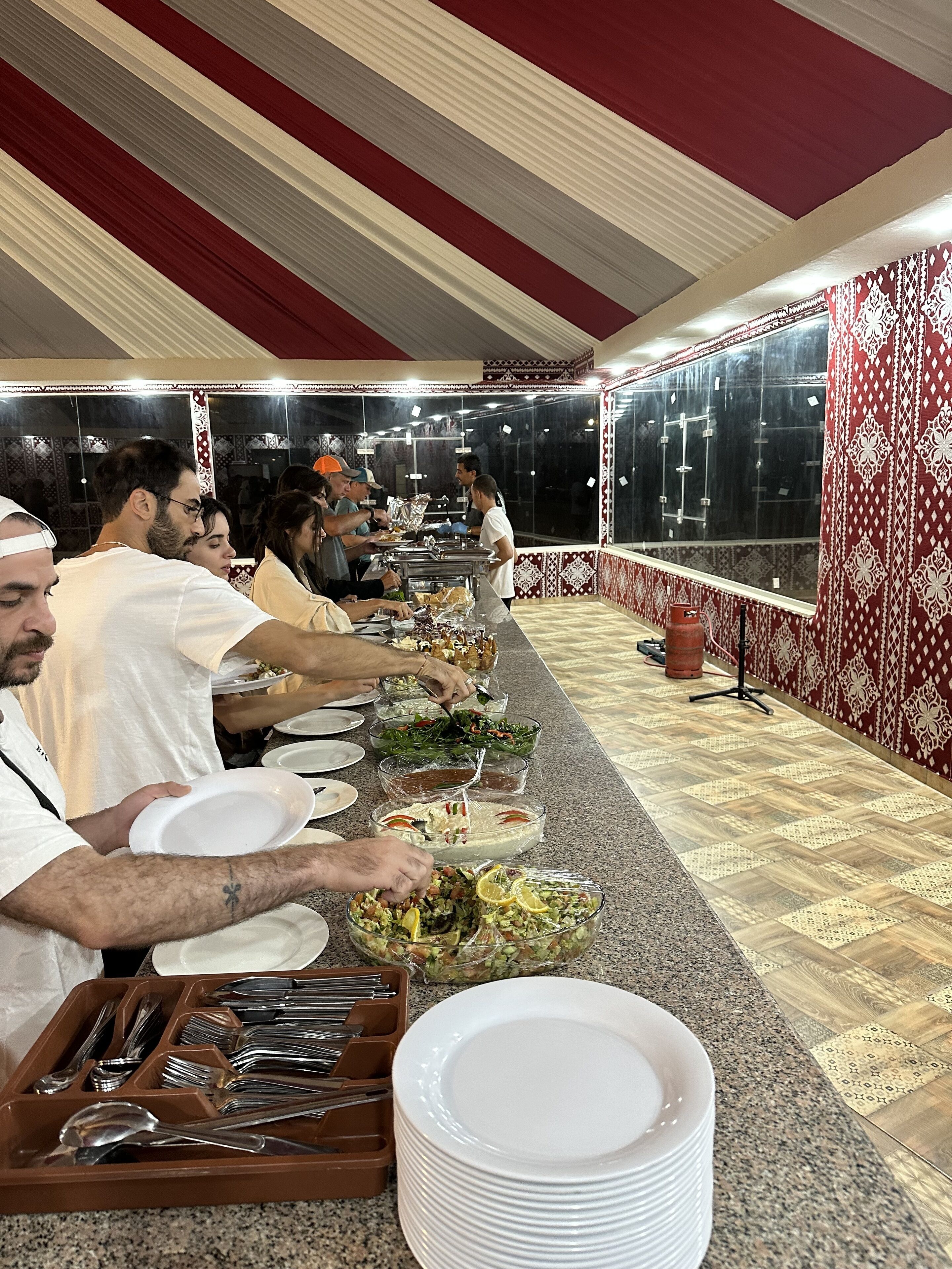 A buffet setup with multiple serving stations, a long counter, and a patterned wall.