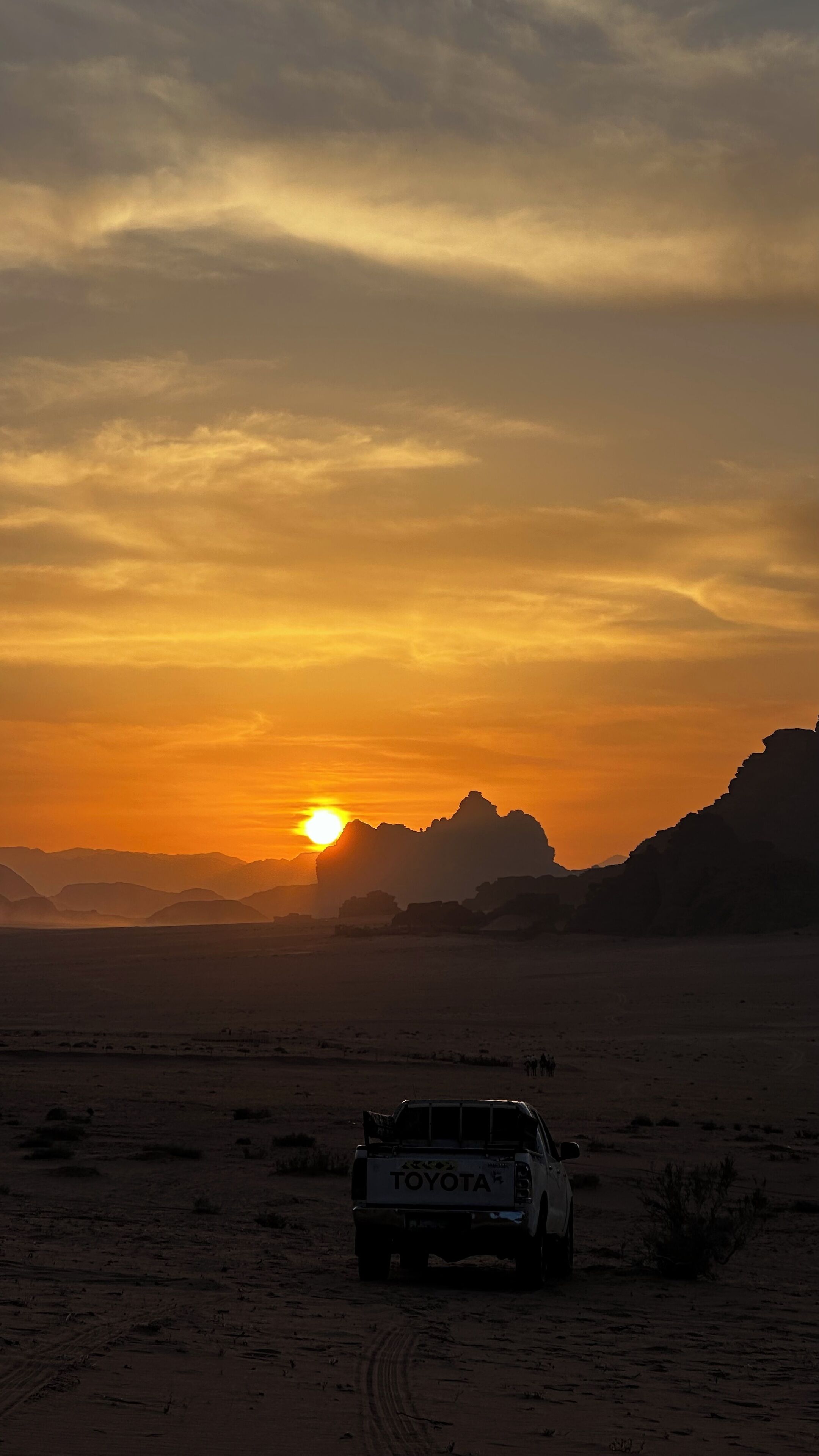 A Toyota vehicle parked in a desert landscape during sunset.
