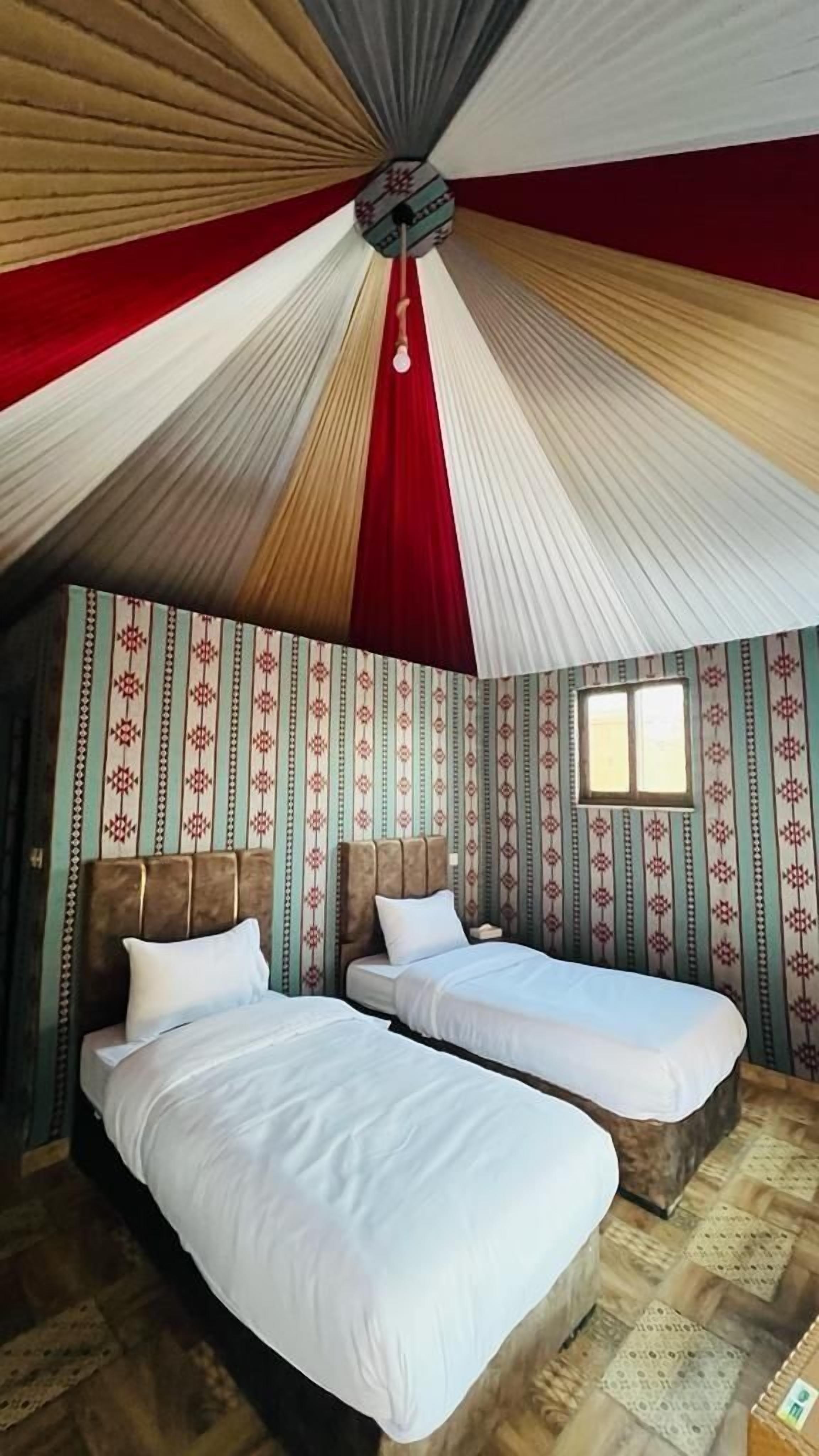 Une chambre avec deux lits, un papier peint à motifs et un décor de plafond original.