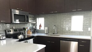 Une cuisine moderne avec des meubles de couleur sombre, des appareils électroménagers en acier inoxydable et un grand îlot central.