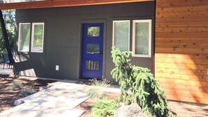 Une maison moderne à deux étages, avec une porte d’entrée bleue, de nombreuses fenêtres et une façade en bois.