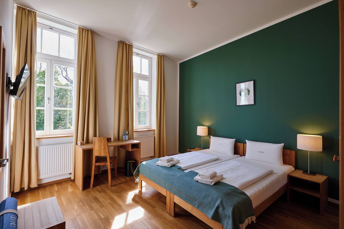 Une chambre d’hôtel équipée d’un lit, d’un bureau, d’une chaise et de deux lampes de chevet.