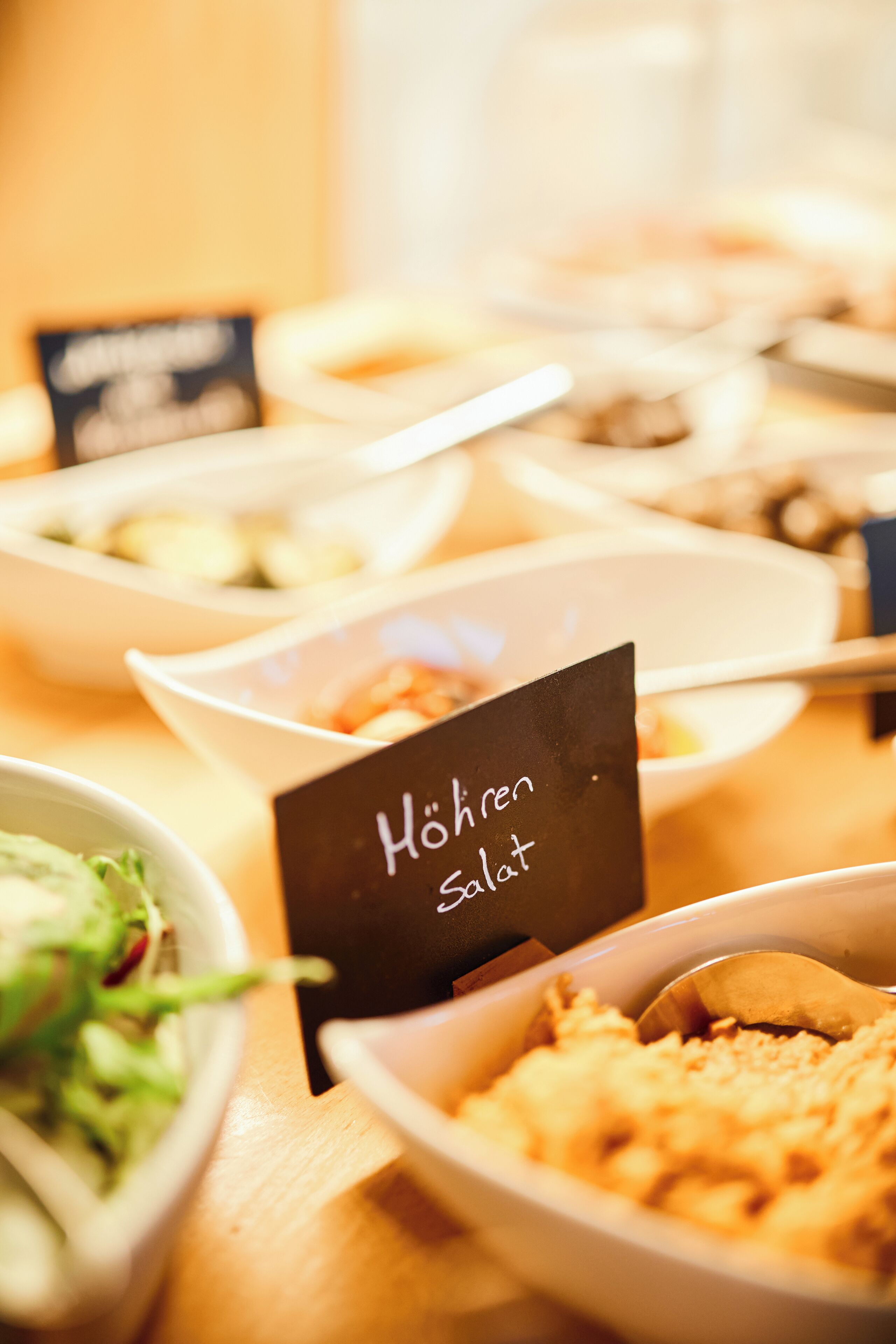 Una taula de buffet amb diversos plats, incloent un cartell que diu 'Hohren Salat'.