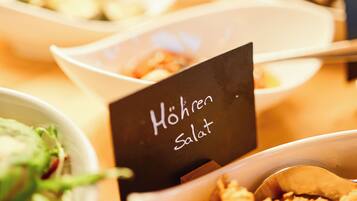Una taula de buffet amb diversos plats, incloent un cartell que diu 'Hohren Salat'.