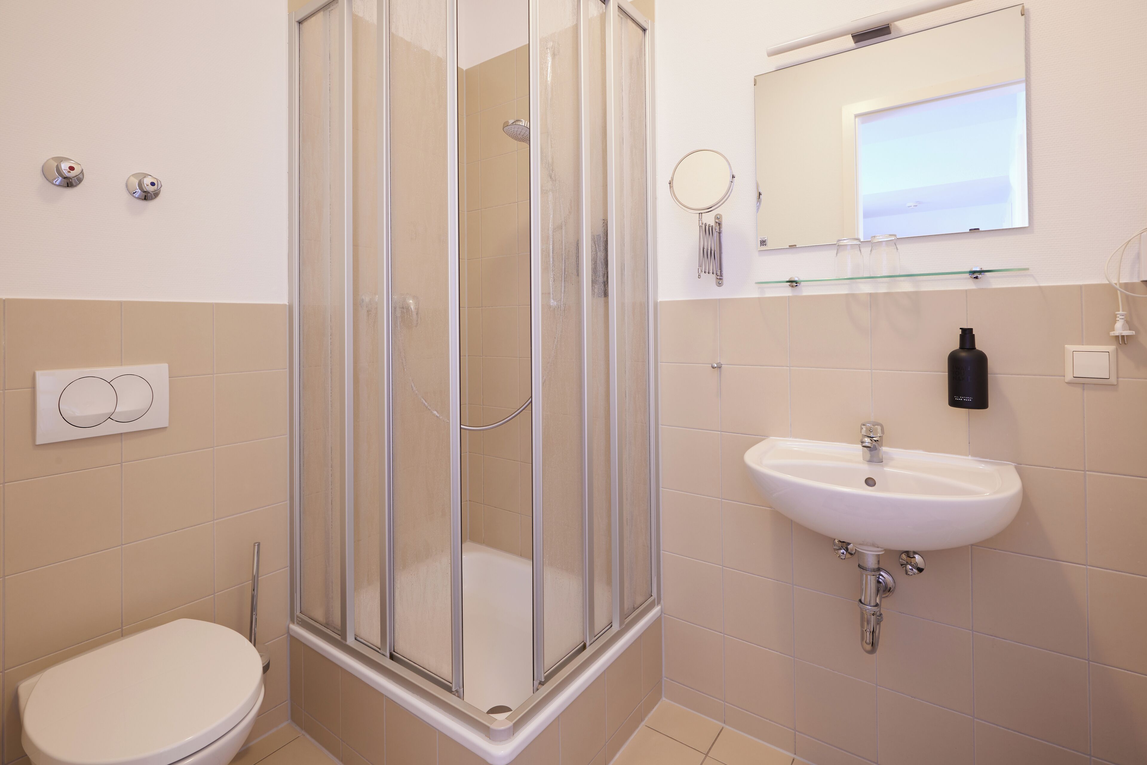 Un bagno con doccia vetrata, un lavandino bianco e un water.