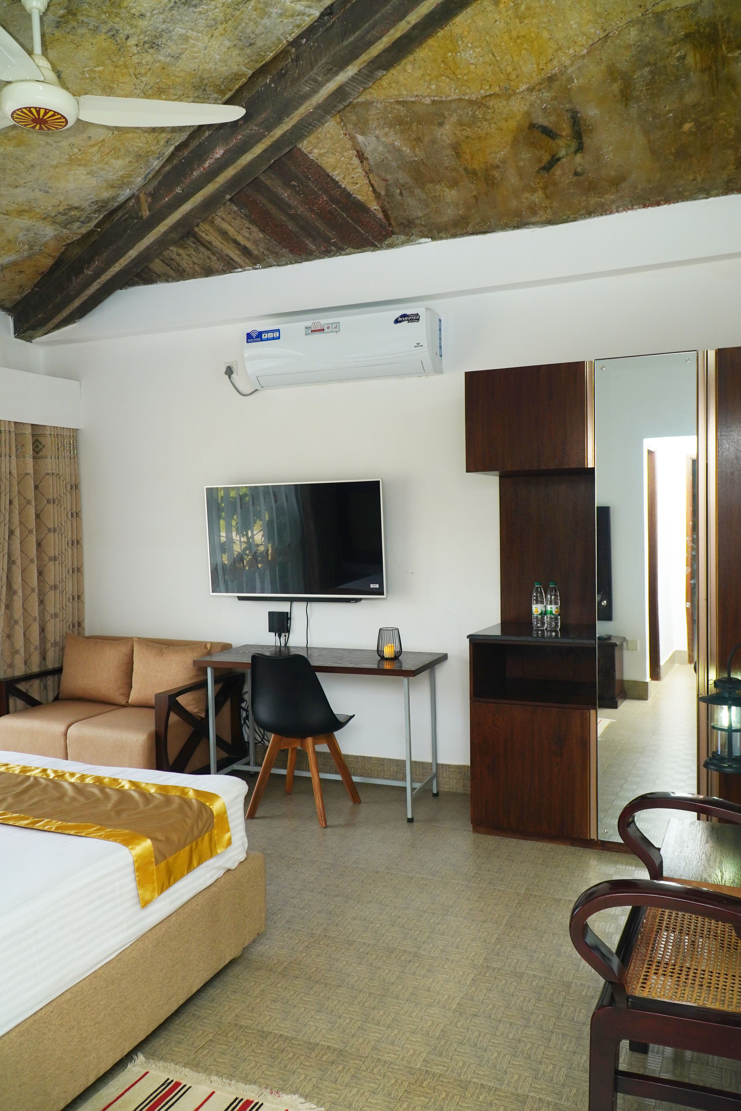 Una camera d'albergo con un letto, una scrivania, una televisione, una sedia e uno specchio.