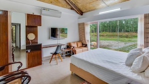 Un dormitorio con cama, escritorio, silla, televisión y vistas al exterior.