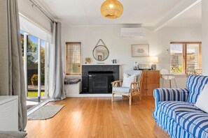 A living room with a fireplace, a sofa, a chair, and a dining area with a table and chairs.