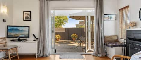 A living room with a television, seating area, and a view to an outdoor patio.