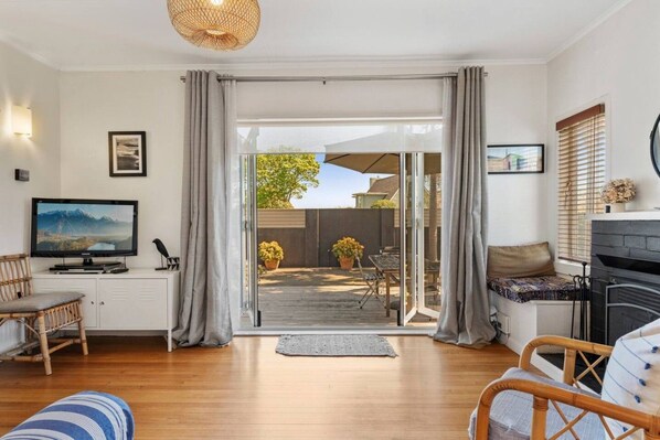 A living room with a television, seating area, and a view to an outdoor patio.