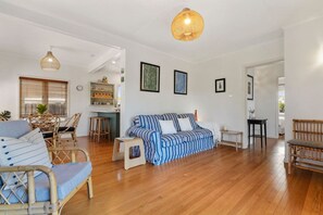 A spacious living area with a sofa, chairs, and a dining table. There is a kitchen area in the background.