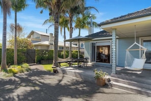 Una casa con un patio, muebles de exterior y una hamaca.