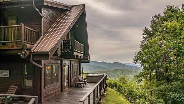 Une cabane en bois dotée d’une terrasse, de grandes fenêtres et offrant une vue sur les montagnes.
