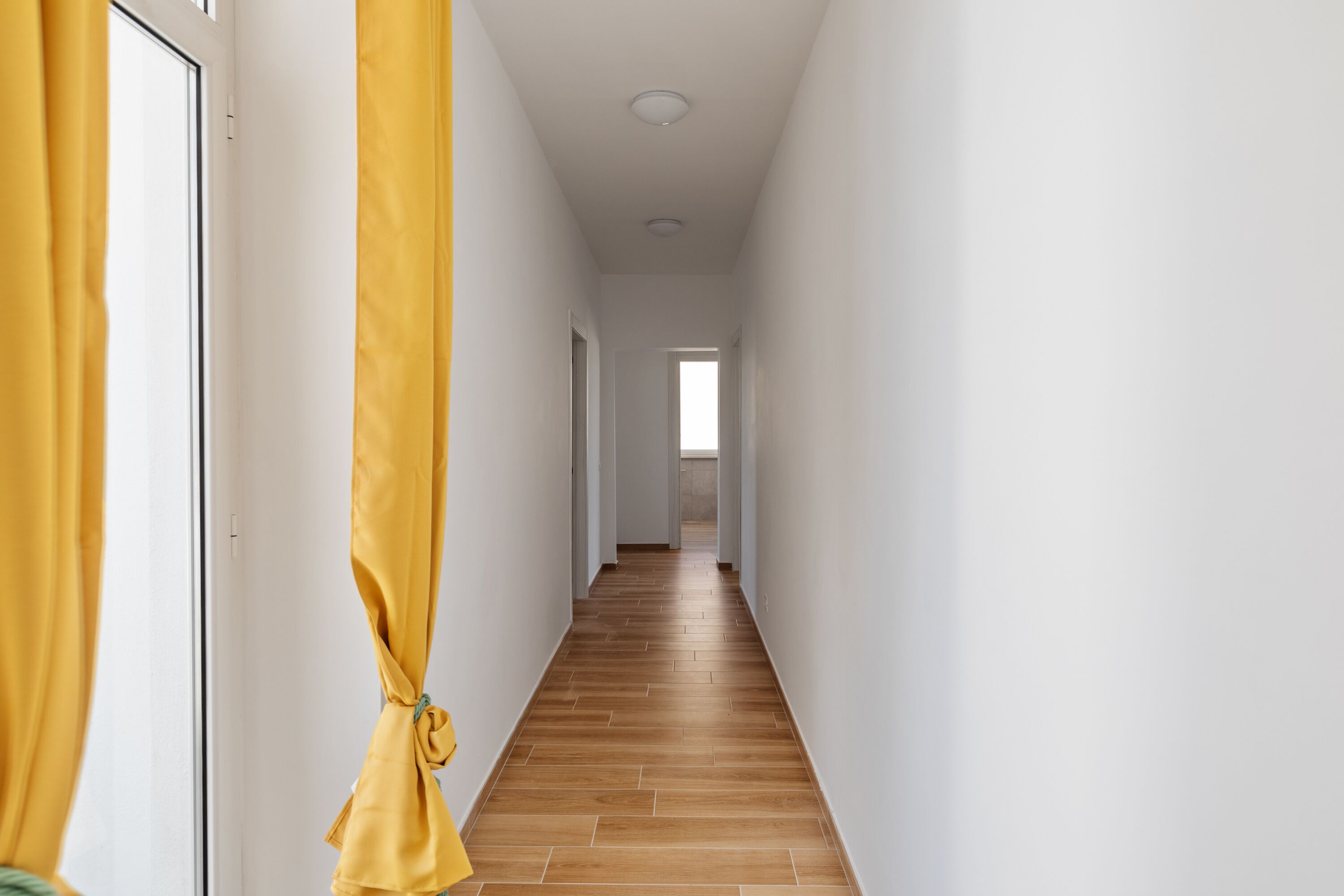 Un couloir avec un plancher en bois et des murs blancs.