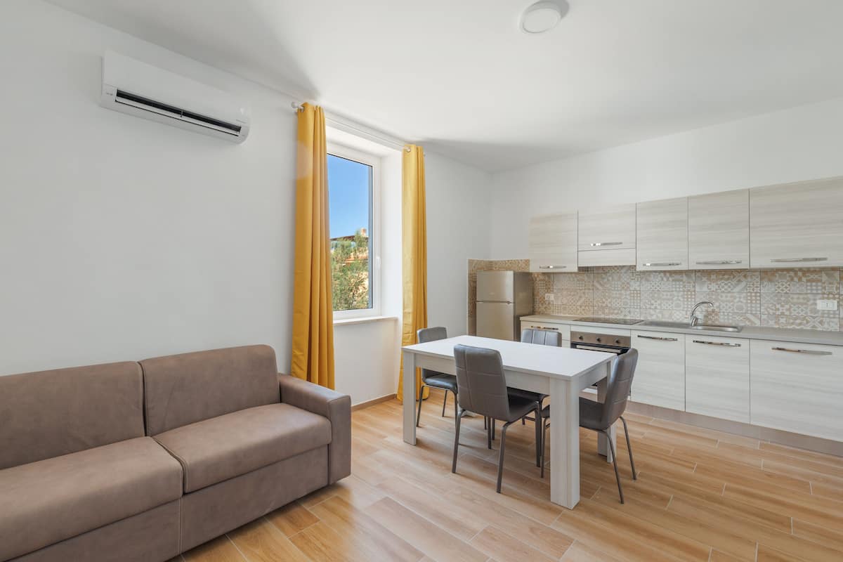 A modern kitchen with white cabinets, a dining table, and a sofa.