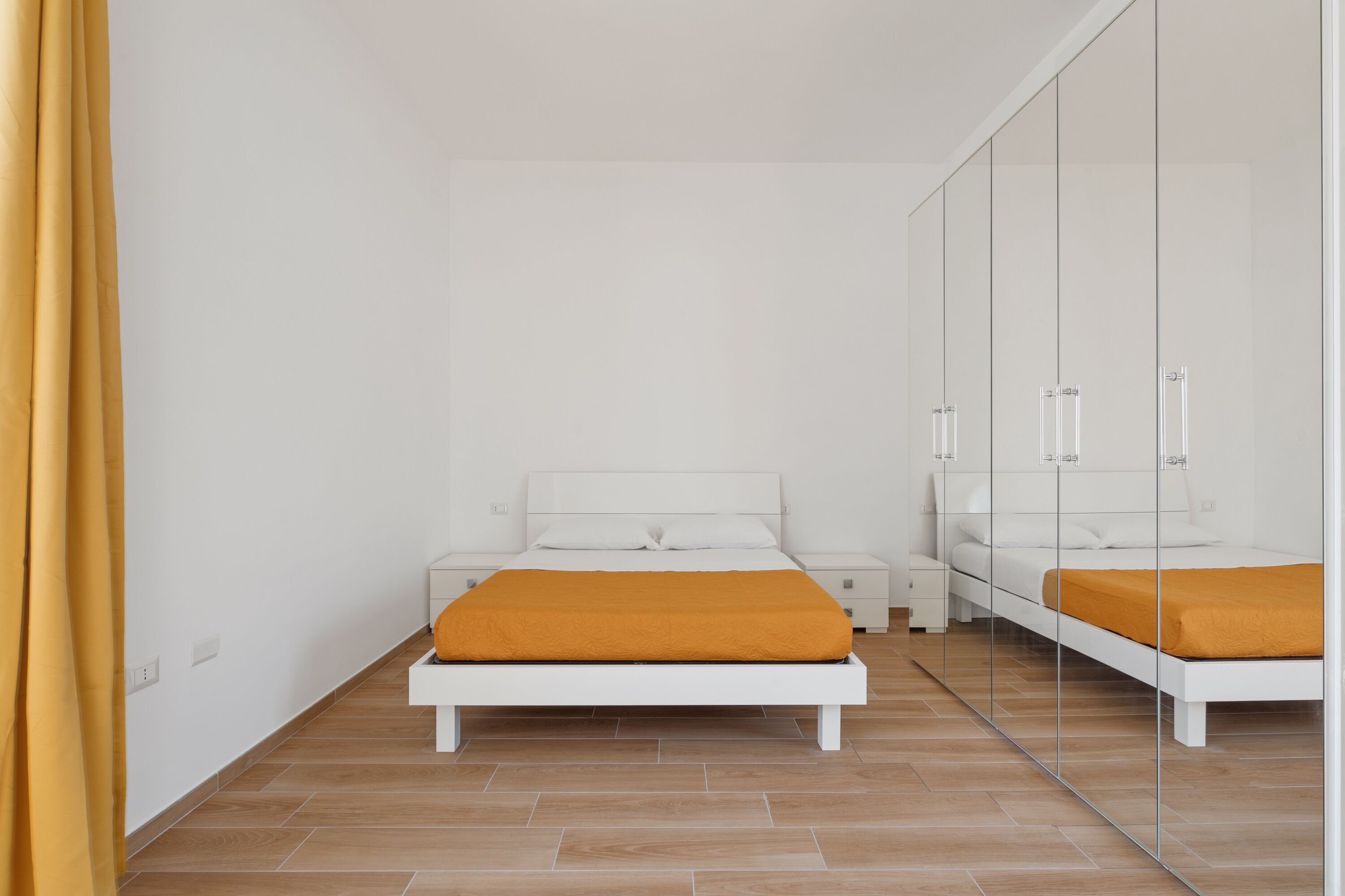 Ein Schlafzimmer mit Bett, Nachttisch, Kleiderschrank und Spiegel.