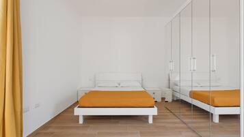 A bedroom with a bed, a nightstand, a wardrobe, and a mirror.