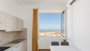 A compact kitchen with a window view, a dining table, and a chair. - Residence Torvaianica (Pomezia)