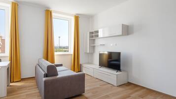 Una sala de estar moderna con sofá, televisor y muebles blancos.