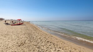 A sandy beach with a red boat and umbrellas. - Residence Torvaianica (Pomezia)
