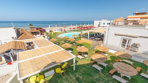 A rooftop pool area with sun loungers and umbrellas, overlooking a beach and the sea. - Residence Torvaianica (Pomezia)