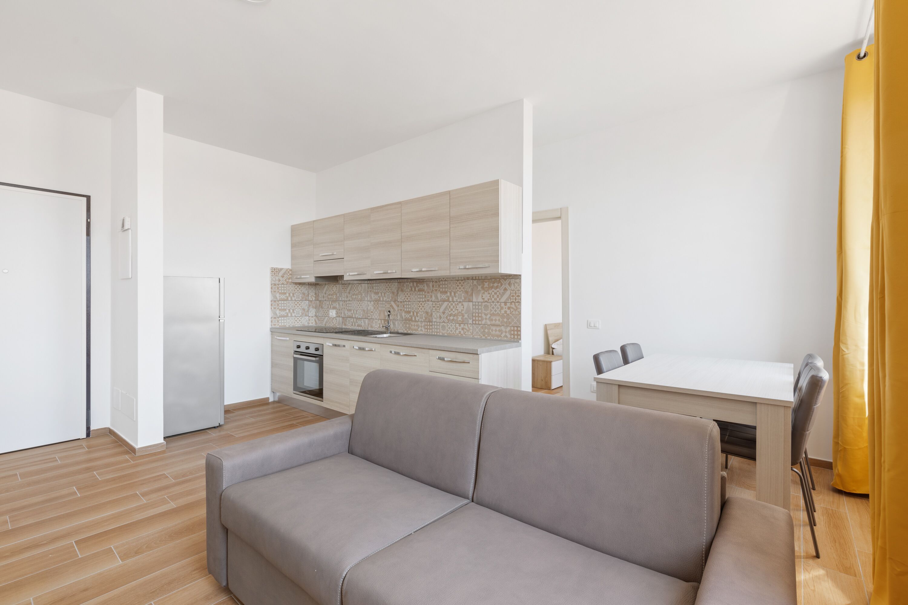 Una cocina moderna con armarios de madera clara, un refrigerador de acero inoxidable y un horno empotrado.