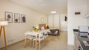 Una habitación moderna y luminosa con comedor, cama y kitchenette.