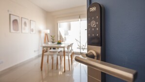 Un interior moderno con cerradura electrónica, una zona de comedor con sillas y una mesa, y obras de arte enmarcadas en la pared.
