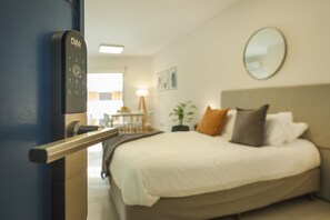 A hotel room with a bed, a bedside table, a lamp, and a mirror on the wall. - Báltico Suites  (Buenos Aires)