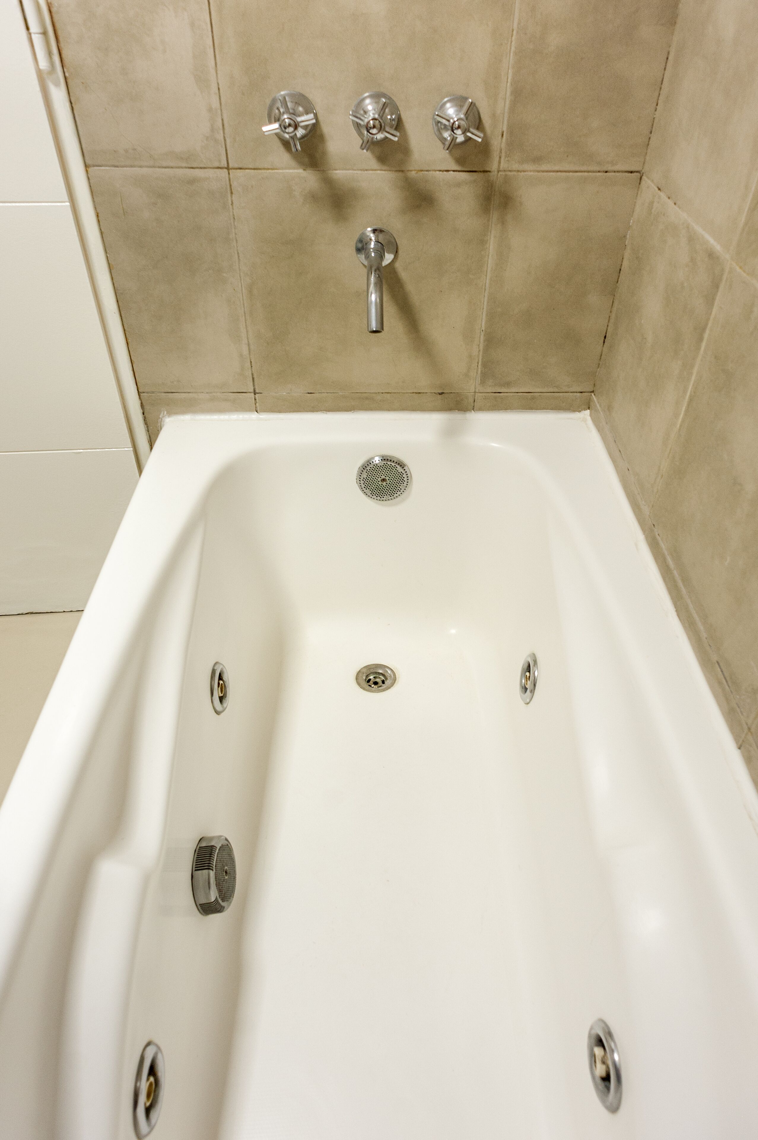 A white bathtub with three faucets and a drain.