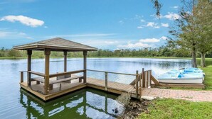 A wooden dock with a covered seating area and a boat on the shore. - Cozy 3 Bedroom Villa Near Disney (Kissimmee)