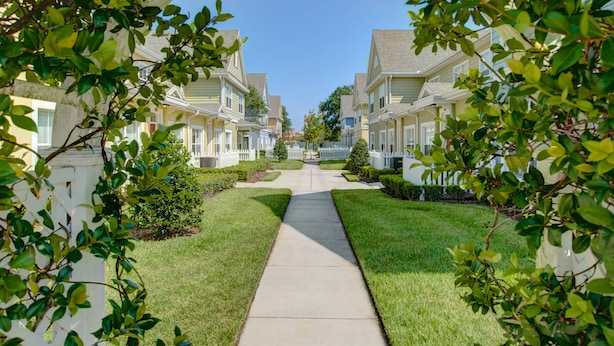 A residential street with houses, a clear sky, and a pathway. - Cozy 3 Bedroom Villa Near Disney (Kissimmee)