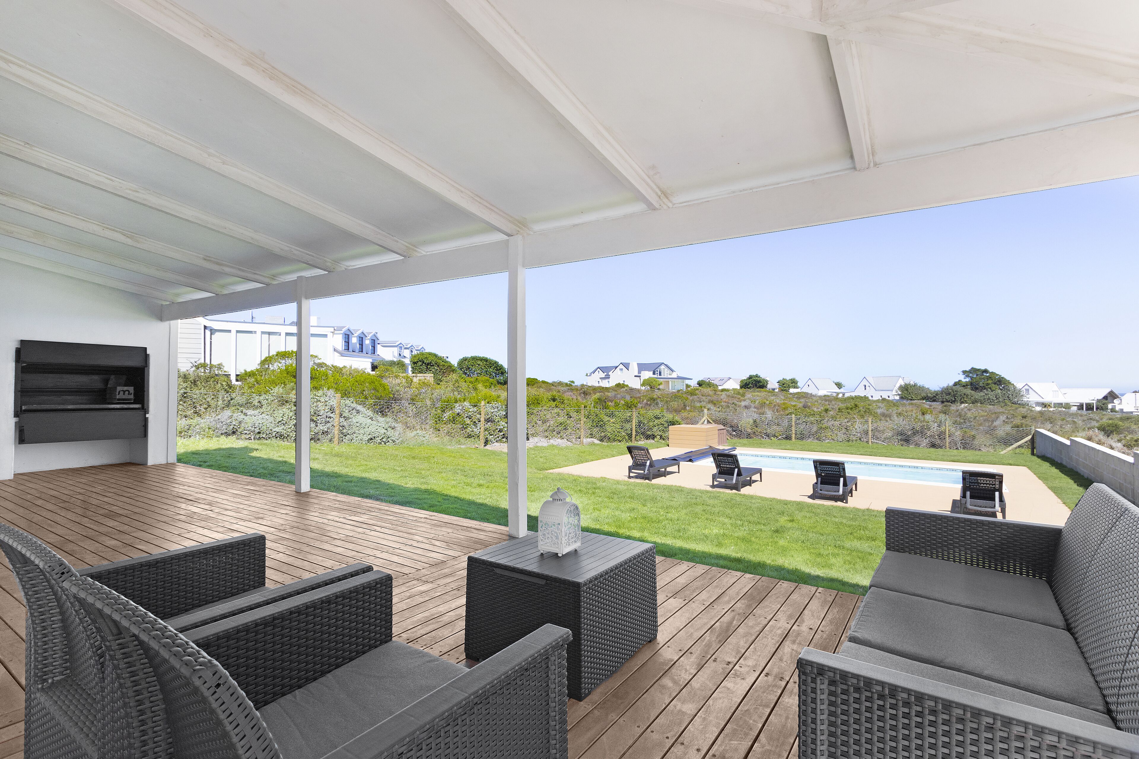 A covered outdoor area with wicker furniture, a pool, and a view of the surrounding landscape.