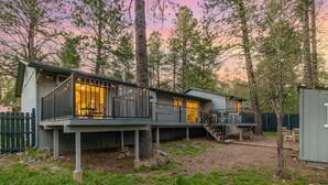 A modern house with a deck, a staircase, and a fenced yard. - Outdoor Oasis: HotTub, Fenced, Firepit & PineTrees (Flagstaff)