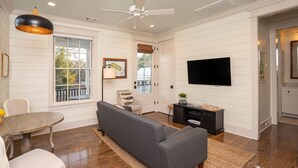 A living room with a sofa, a dining table, a TV, and a ceiling fan. - The Harrington in downtown Beaufort  (Beaufort)
