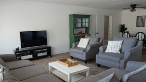 A living room with grey sofas, a white coffee table, a TV on a black stand, and a green cabinet. - Emerald Lake House- Boat Parking with a View of the Vermillion Cliffs (Page)