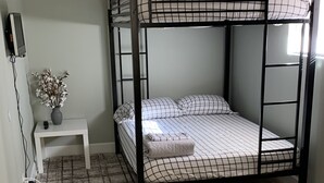 A bunk bed with a checkered mattress, a small white bedside table with a vase, and a wooden floor. - Emerald Lake House- Boat Parking with a View of the Vermillion Cliffs (Page)