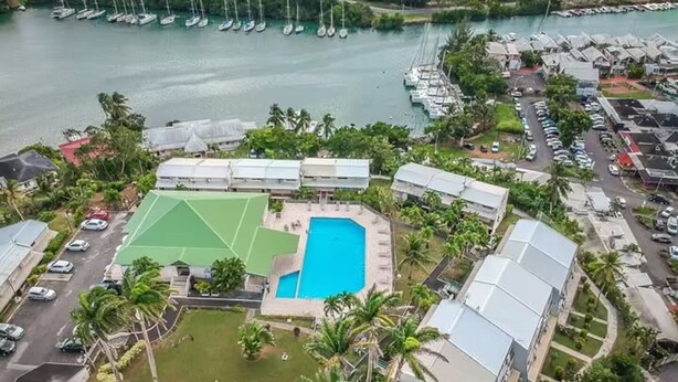 A resort with a swimming pool, tennis court, and a marina with boats. - Super Appartement Avec Piscine, en Plein Coeur du Centre Ville de la Marina (Le Gosier)