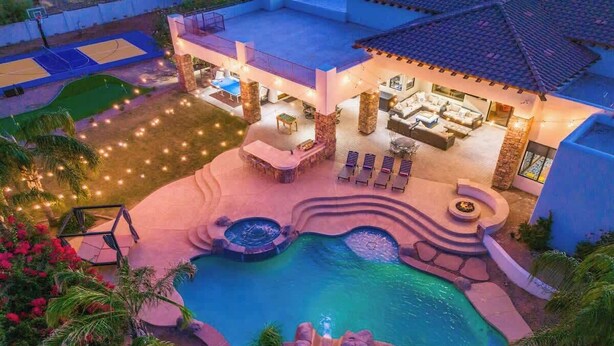 Una piscina con cascata, una zona relax coperta con un braciere e un campo da basket.
