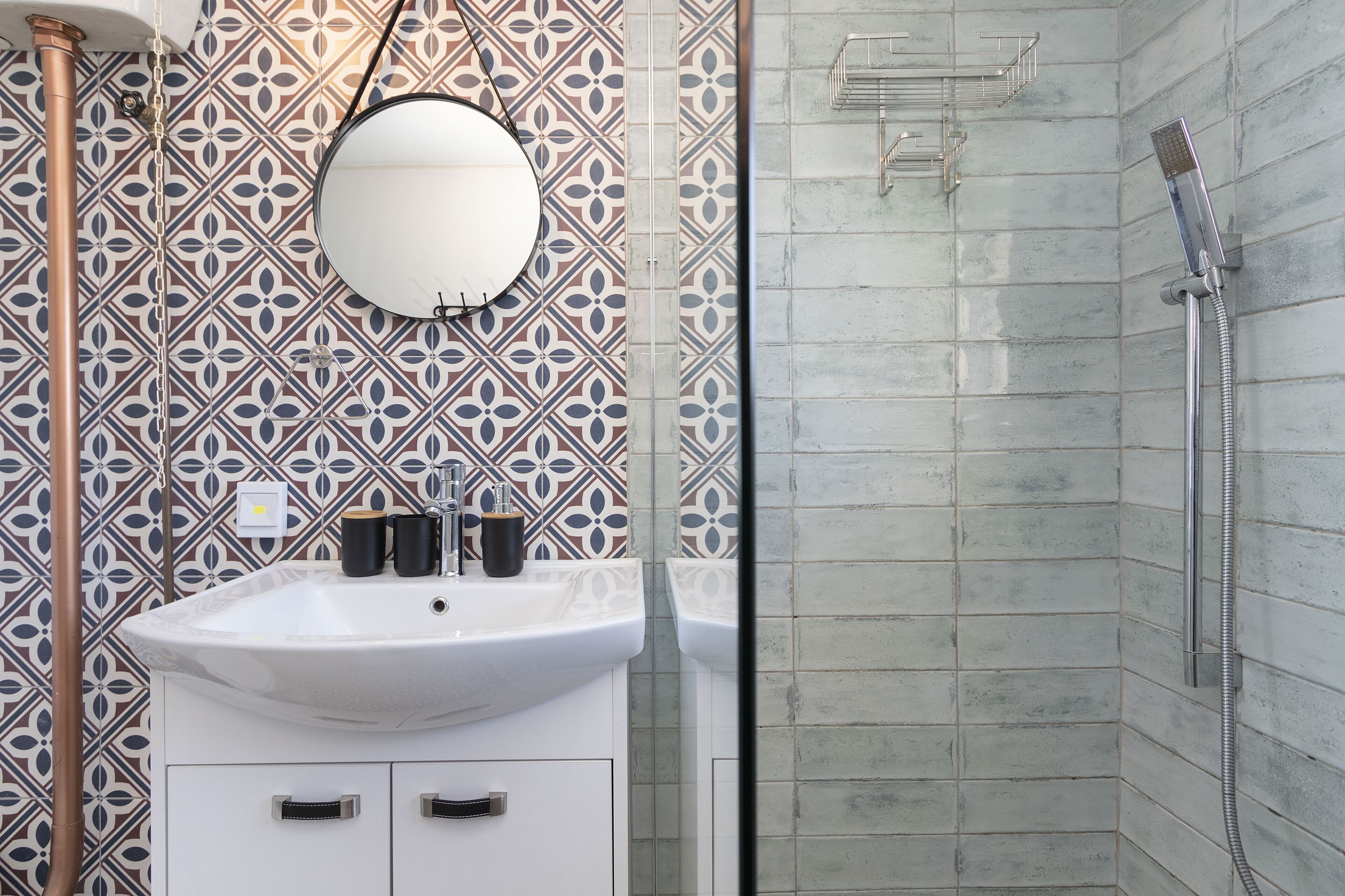A bathroom with a white sink, a round mirror, and a shower area.