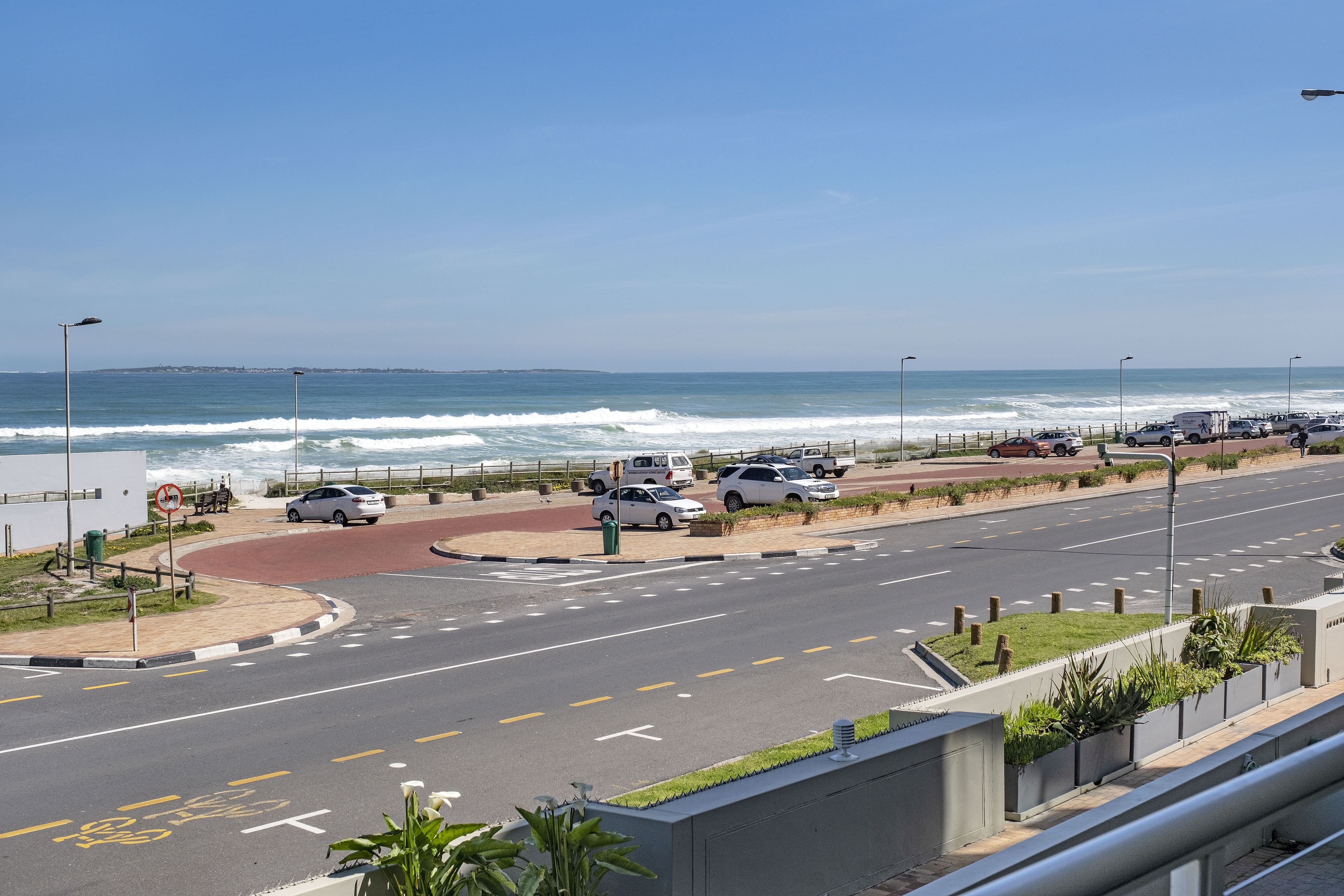 A coastal road with a roundabout, vehicles, and a view of the ocean.