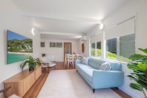 Una sala de estar moderna con un sofá azul claro, una consola de madera y un televisor de pantalla plana grande montado en la pared.