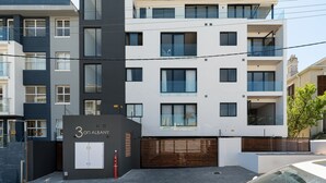 Een modern meerlaags gebouw met een opvallende ingang, aangeduid met '3 on Albany'.