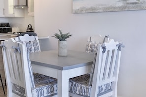A dining table with six chairs, each with striped cushions. A potted plant is on the table.